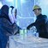 A bartender serving 2 people in a bar made entirely of ice